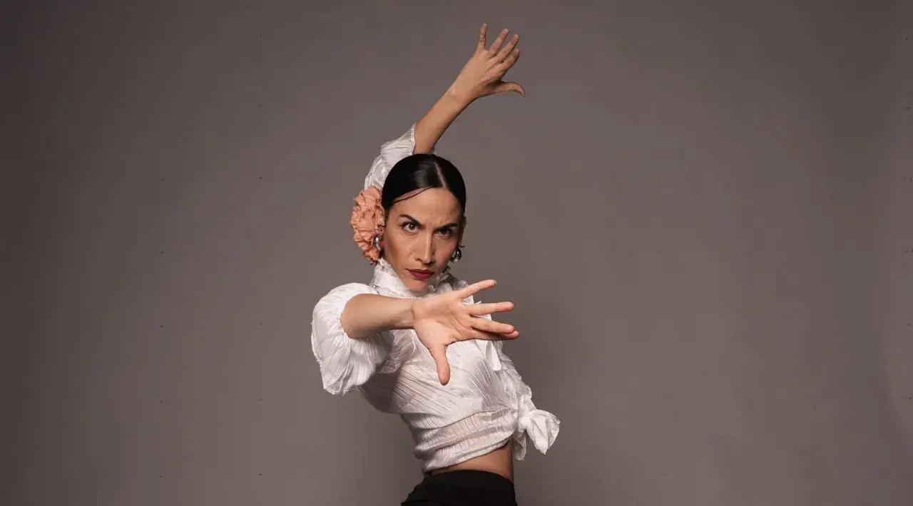 Bailarina de flamenco con flor en el pelo, ejecutando elegantes pasos de flamenco con expresión intensa.