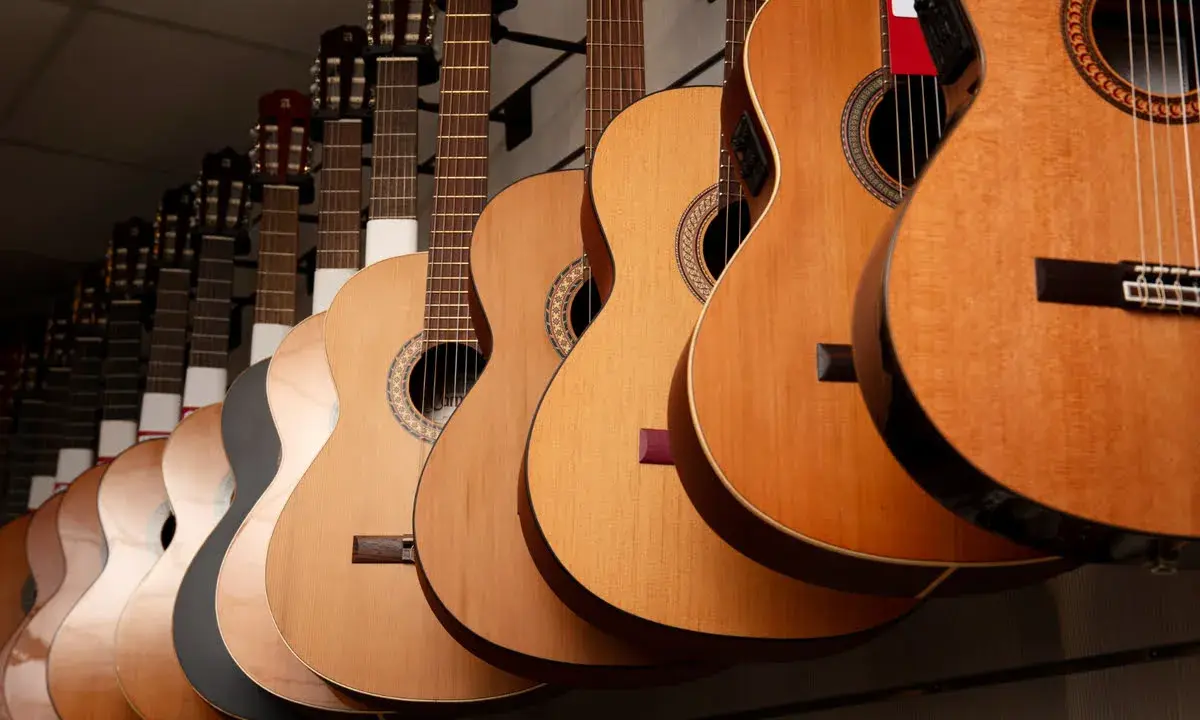Varias guitarras cuelgan en fila, mostrando la diferencia entre guitarra española y flamenca.