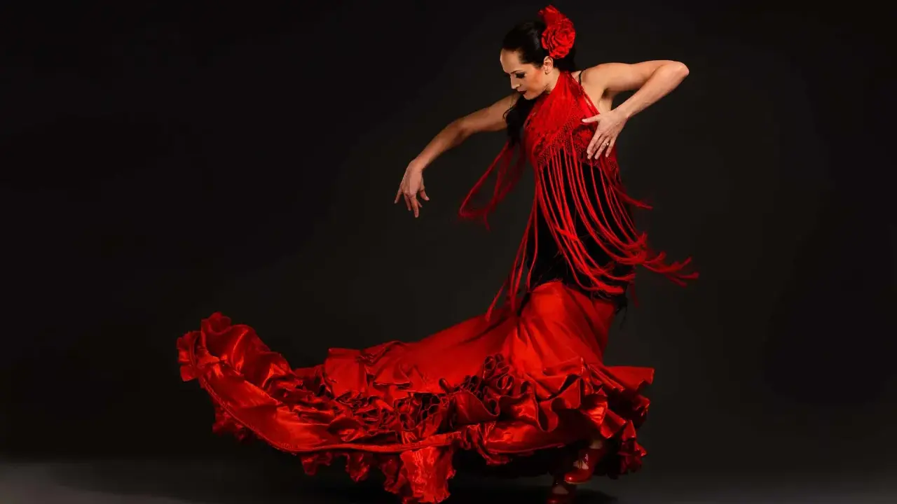Bailarina de flamenco con vestido rojo voluminoso y mantón de flecos. Un ejemplo de las curiosidades del flamenco, su pasión y elegancia.