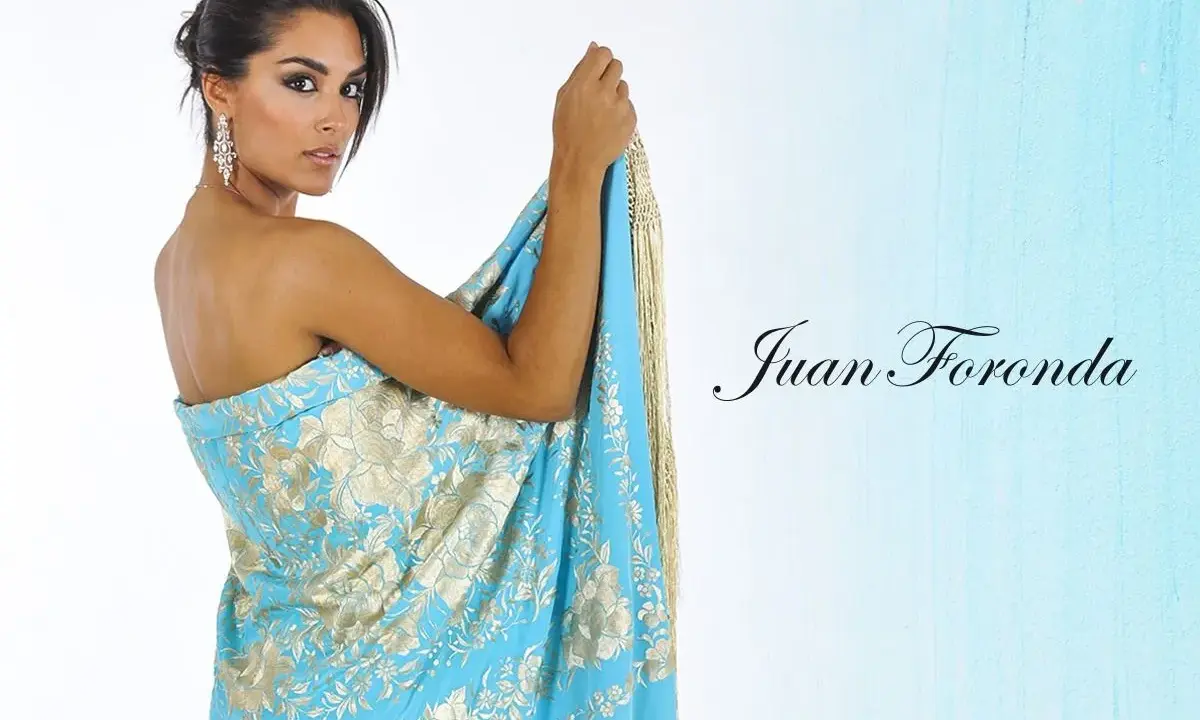 Mujer con mantón de Manila azul turquesa con bordados dorados, mostrando cómo colocar un mantón de manila como vestido.
