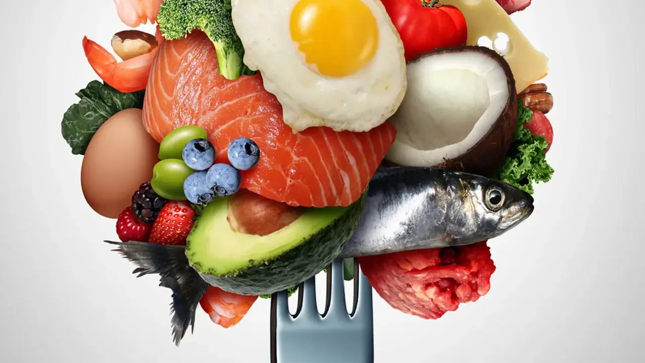 Un tenedor carga una variedad de alimentos saludables, incluyendo salmón, aguacate, huevo, bayas y verduras bajas en carbohidratos, ideal para una dieta equilibrada.