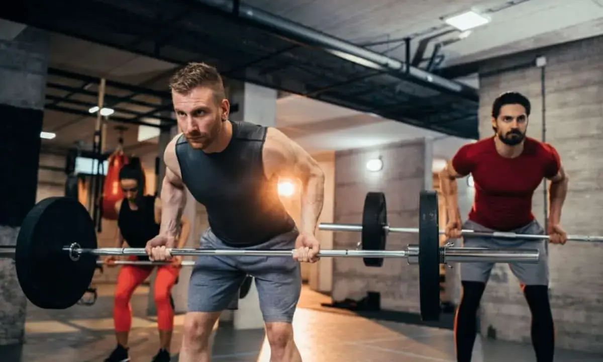 Hombres y mujeres realizando ejercicios de espalda en el gym con barras.