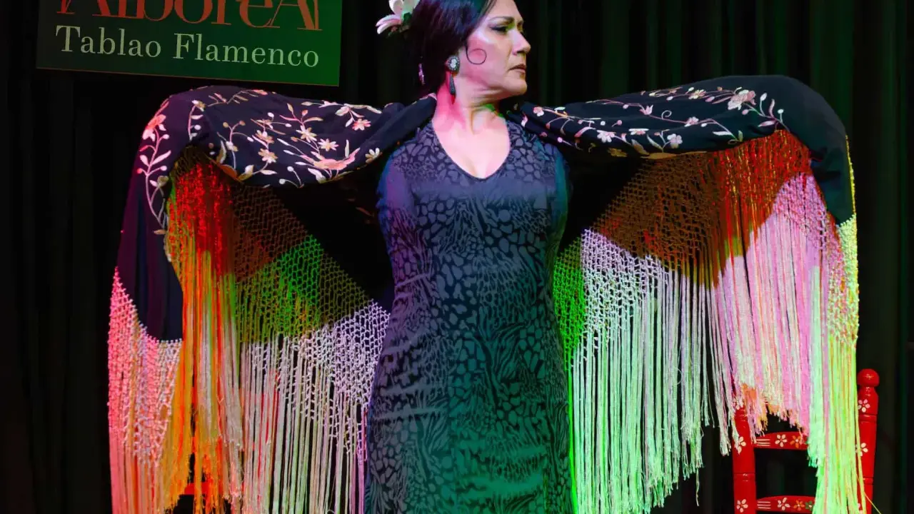 Una bailaora flamenca, con un mantón bordado y flecos de colores, se prepara para su actuación en el tablao Alborea.