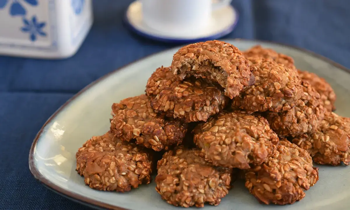 Montón de galletas proteicas caseras en un plato, con una taza de café al fondo. ¡Una deliciosa receta de cookies proteicas!