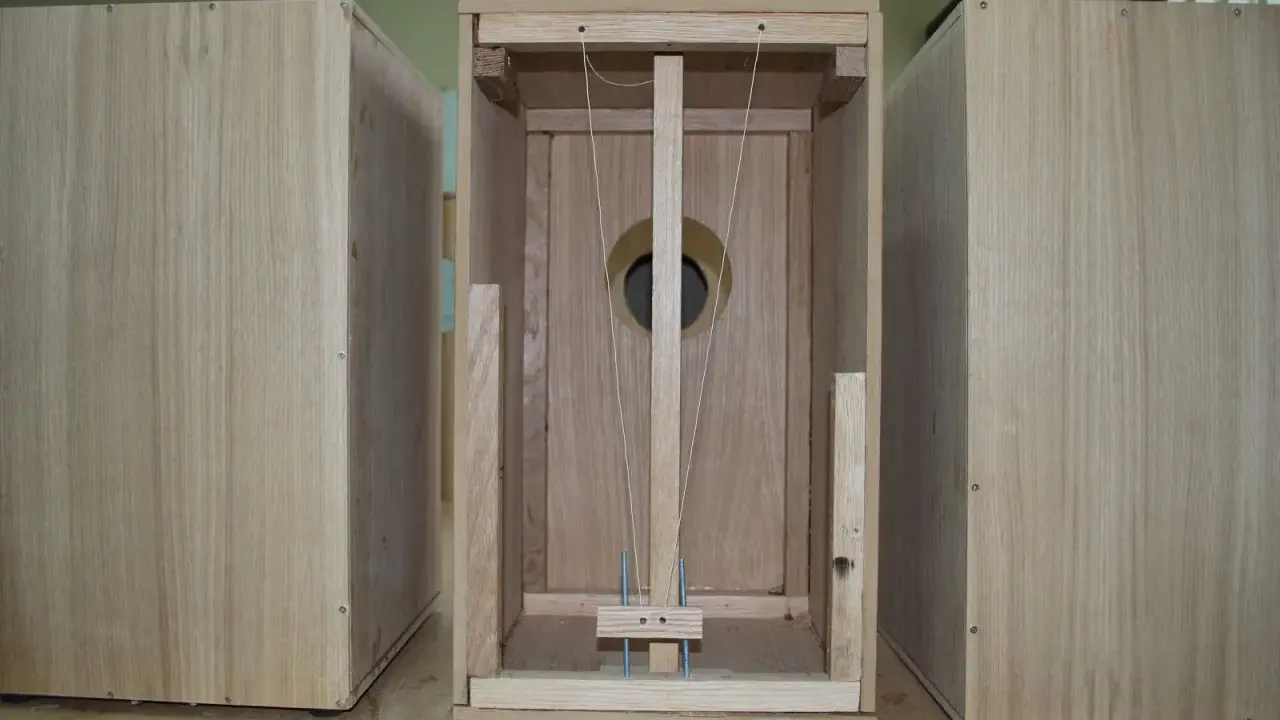 Partes de un cajón de madera, mostrando la estructura interna con cuerdas y un agujero circular.