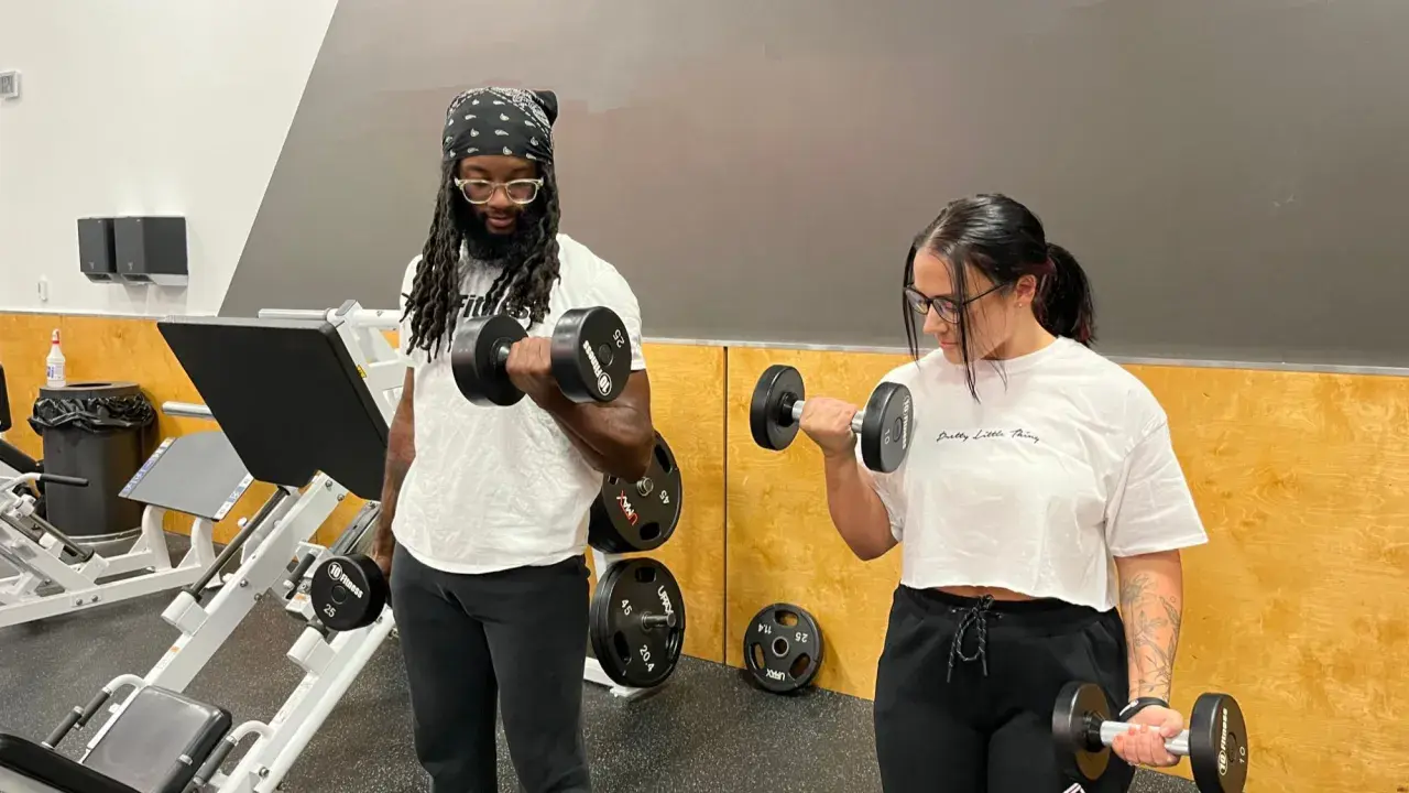 Pareja entrenando fuerza en el gimnasio, levantando pesas.