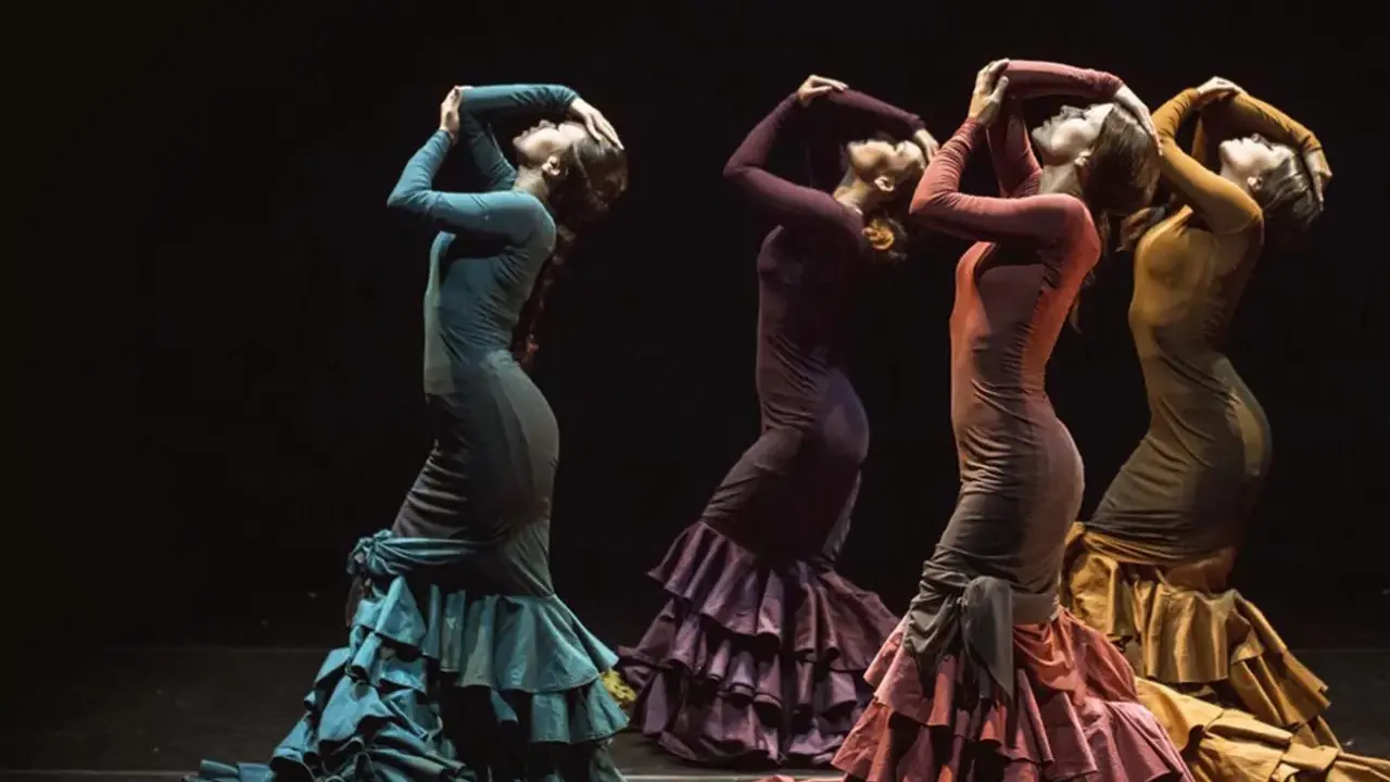 Cuatro mujeres flamencas bailando con vestidos de volantes en tonos tierra.