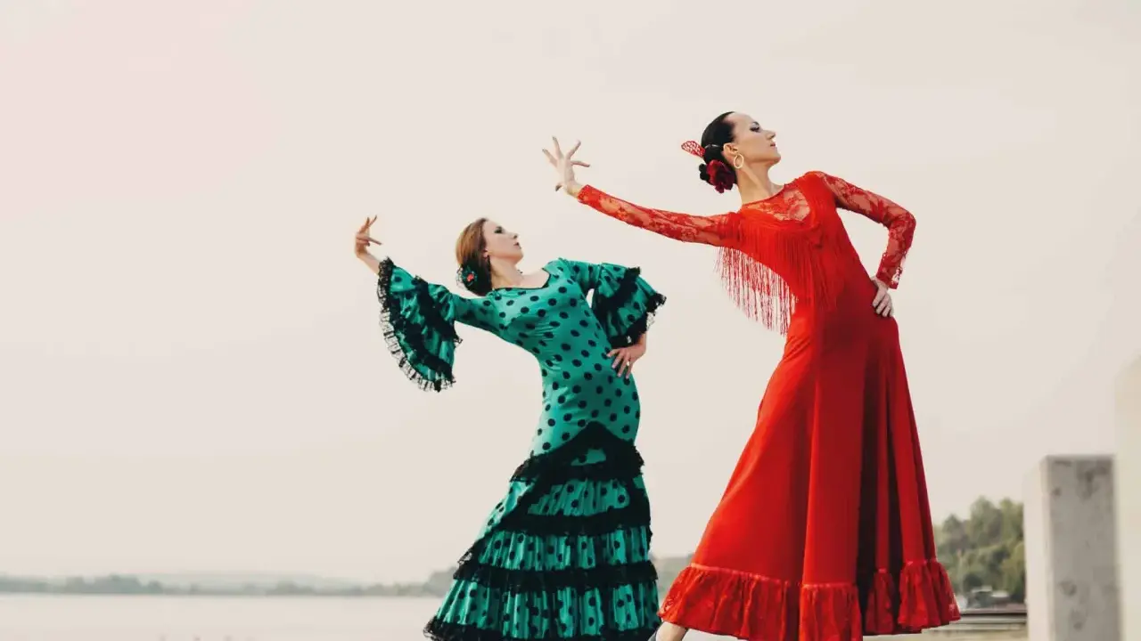 Dos bailarinas de flamenco, una con vestido verde de lunares y otra con rojo vibrante, ejecutan un apasionado flamenco ballo.