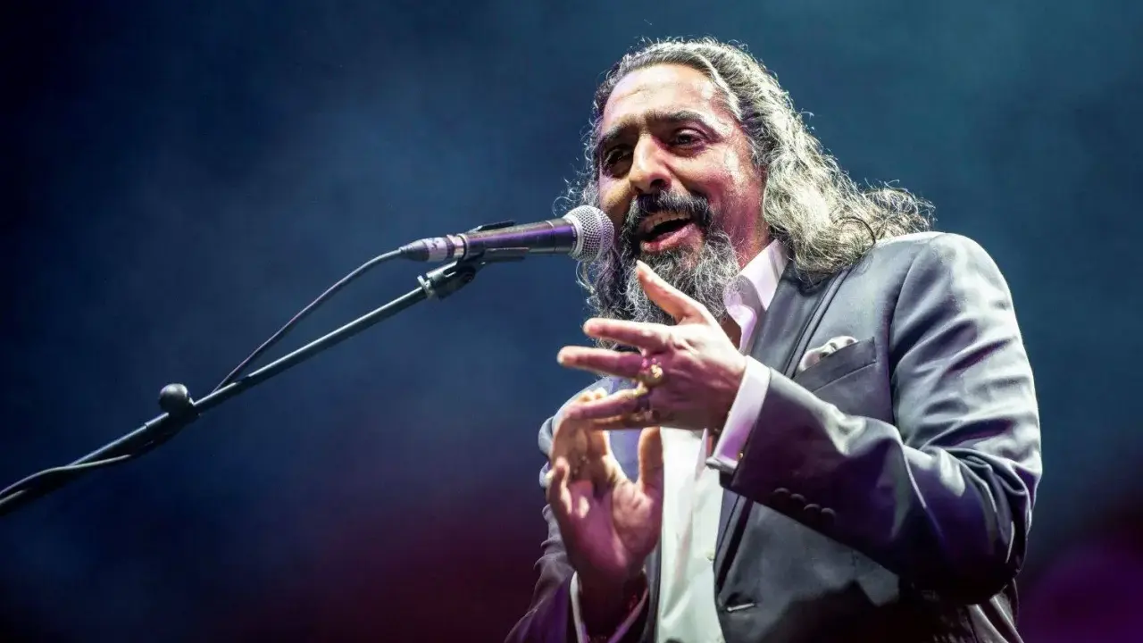 Un cantaor gitano, con su voz profunda y gestos apasionados, cautiva al público en el escenario.
