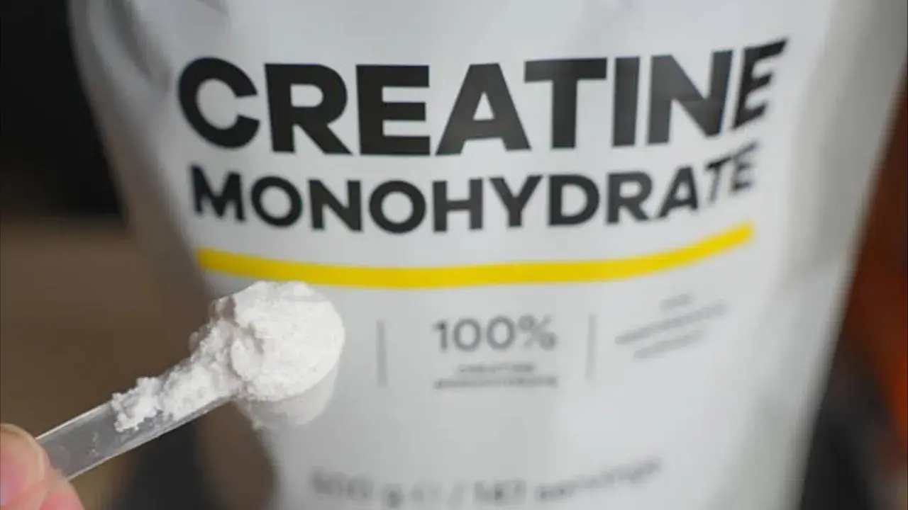 Bolsa de creatina monohidrato con una cuchara llena de polvo blanco. Ideal para potenciar tus músculos.