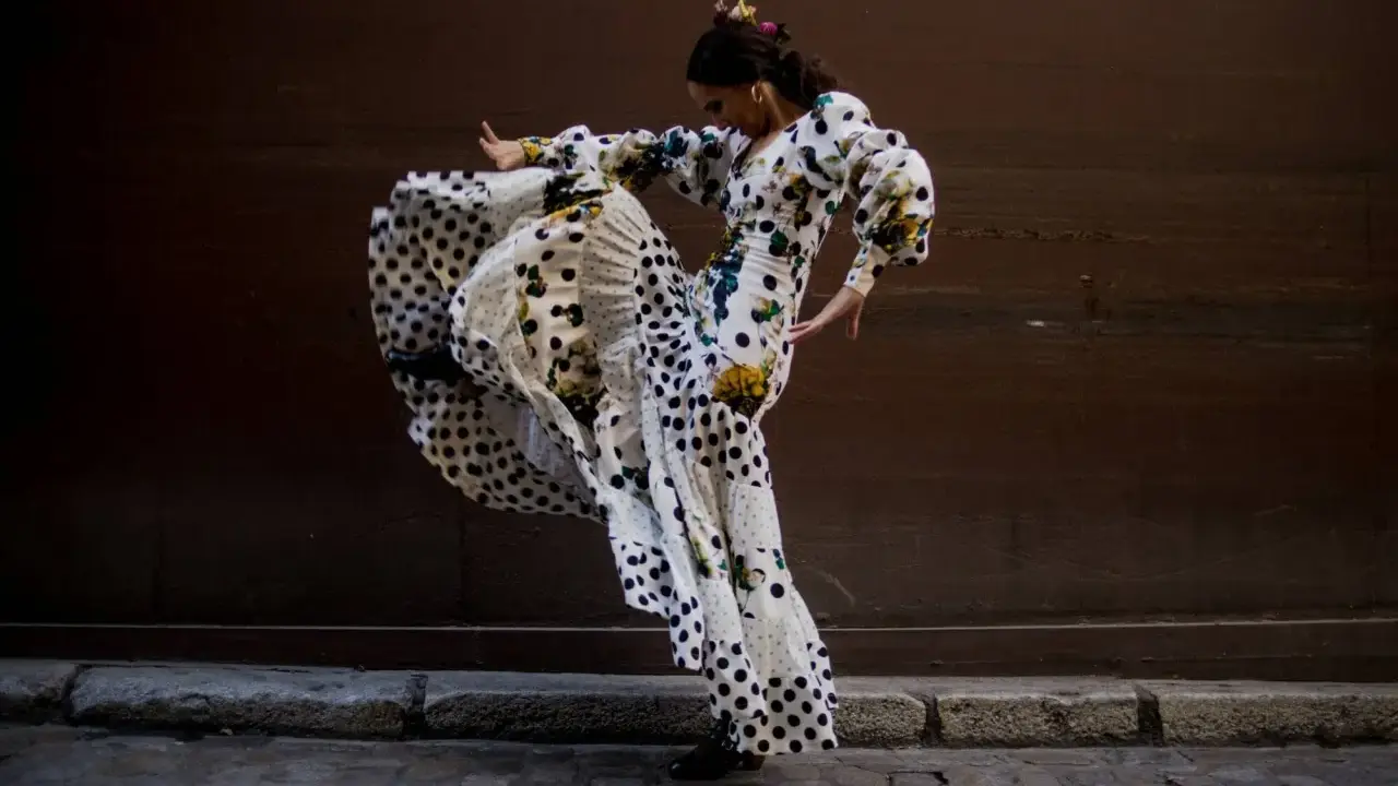Bailarina de flamenco con vestido de lunares y volantes, capturando la esencia del flamenco origine en un movimiento apasionado.