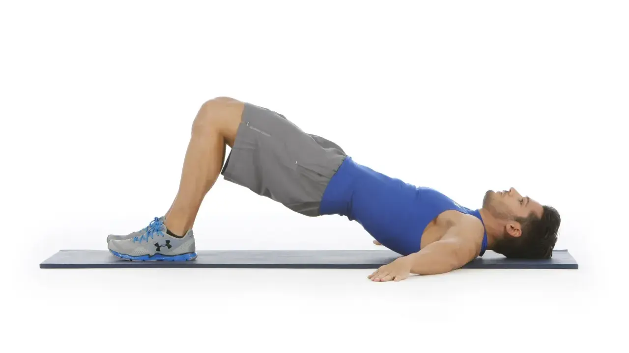 Hombre realizando puente de glúteo, un ejercicio clave para fortalecer la zona lumbar en el gym.