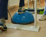 Persona practica ejercicios de equilibrio sobre una pelota azul, una forma de como regular el sistema nervioso y mejorar la coordinación.