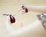 Manos sujetando castañuelas, un instrumento musical tradicional, listas para crear ritmos vibrantes.