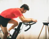 Hombre en bicicleta estática, entrenando para mejorar su artrosis de rodilla.