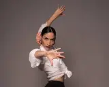 Bailarina de flamenco con flor en el pelo, ejecutando elegantes pasos de flamenco con expresión intensa.