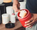 Hombre preparando un batido con suplementos. La creatina aumenta la masa muscular, clave para el entrenamiento.