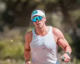 Atleta con gafas deportivas y visera, concentrado en como correr por un sendero.