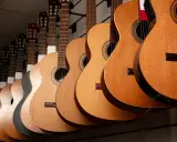 Varias guitarras cuelgan en fila, mostrando la diferencia entre guitarra española y flamenca.