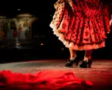 Pies de bailaora con volantes de lunares y flores, listos para un apasionado baile por bulerías.