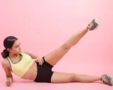 Mujer haciendo ejercicio, levantando una pierna para trabajar el **parte interna del muslo**.