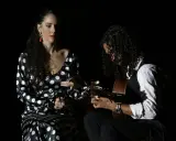 Una bailaora flamenca con vestido de lunares y un guitarrista crean un duende que es pura pasión en la oscuridad.