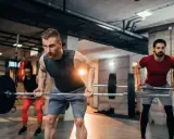 Hombres y mujeres realizando ejercicios de espalda en el gym con barras.