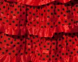 Falda roja con lunares negros, con volantes y cintas, ideal para un baile típico de Sevilla.