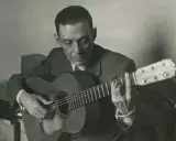 Un guitarrista flamenco andaluz, con traje y corbata, toca su guitarra con pasión.