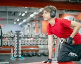 Joven con auriculares entrena en gimnasio. ¿Hacer pesas a los 15 años detiene mi crecimiento?