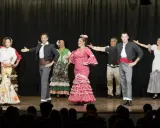 Artistas de sevillanas y flamenco en escena, con trajes coloridos y movimientos apasionados.