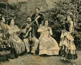 Grupo de músicos y bailarinas, una de ellas realiza un zambra baile gitano, con guitarras y mantones.