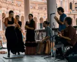 Artistas flamencos crean un jaleo de música y baile en una plaza.