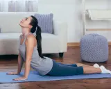 Mujer realizando estiramientos lumbares en posición de cobra sobre una esterilla azul en una sala de estar.