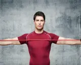 Hombre realizando ejercicios de pecho con gomas elásticas rojas, estirándolas hacia los lados.