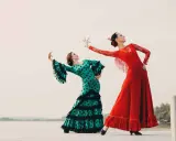 Dos bailarinas de flamenco, una con vestido verde de lunares y otra con rojo vibrante, ejecutan un apasionado flamenco ballo.