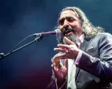 Un cantaor gitano, con su voz profunda y gestos apasionados, cautiva al público en el escenario.