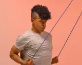 Hombre con cabello rizado haciendo ejercicio con banda elástica para mejorar la movilidad tren superior.