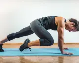 Mujer haciendo mountain climbers en una esterilla azul.