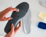 Manos aplicando vaselina en una plantilla para zapatos, un método para como quitar ruido zapatos goma.