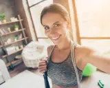Sonriendo mujer con cuerda de saltar, lista para disfrutar los beneficios de saltar a la comba.