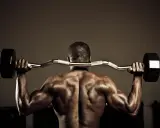 Hombre musculoso con barra detrás del cuello, trabajando para fortalecer lumbares.