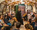 Una bailaora de flamenco, con un vestido negro de lunares, actúa en un local íntimo donde se baila flamenco. Un guitarrista la acompaña.