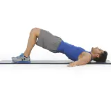 Hombre realizando puente de glúteo, un ejercicio clave para fortalecer la zona lumbar en el gym.