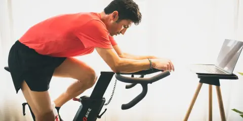 Hombre en bicicleta estática, entrenando para mejorar su artrosis de rodilla.
