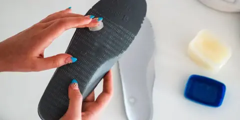 Manos aplicando vaselina en una plantilla para zapatos, un método para como quitar ruido zapatos goma.