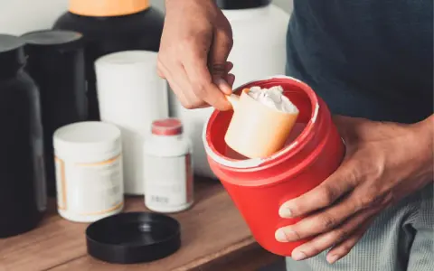 Hombre preparando un batido con suplementos. La creatina aumenta la masa muscular, clave para el entrenamiento.