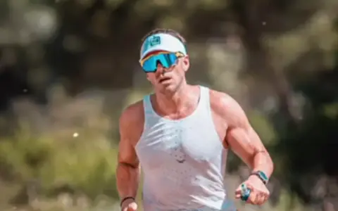 Atleta con gafas deportivas y visera, concentrado en como correr por un sendero.