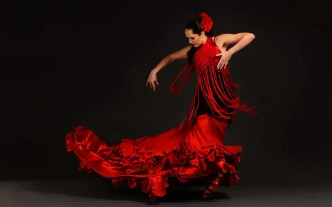 Bailarina de flamenco con vestido rojo voluminoso y mantón de flecos. Un ejemplo de las curiosidades del flamenco, su pasión y elegancia.