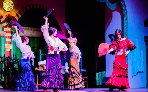 Bailarinas de flamenco con abanicos desplegados, mostrando las partes de un abanico en un espectáculo vibrante.
